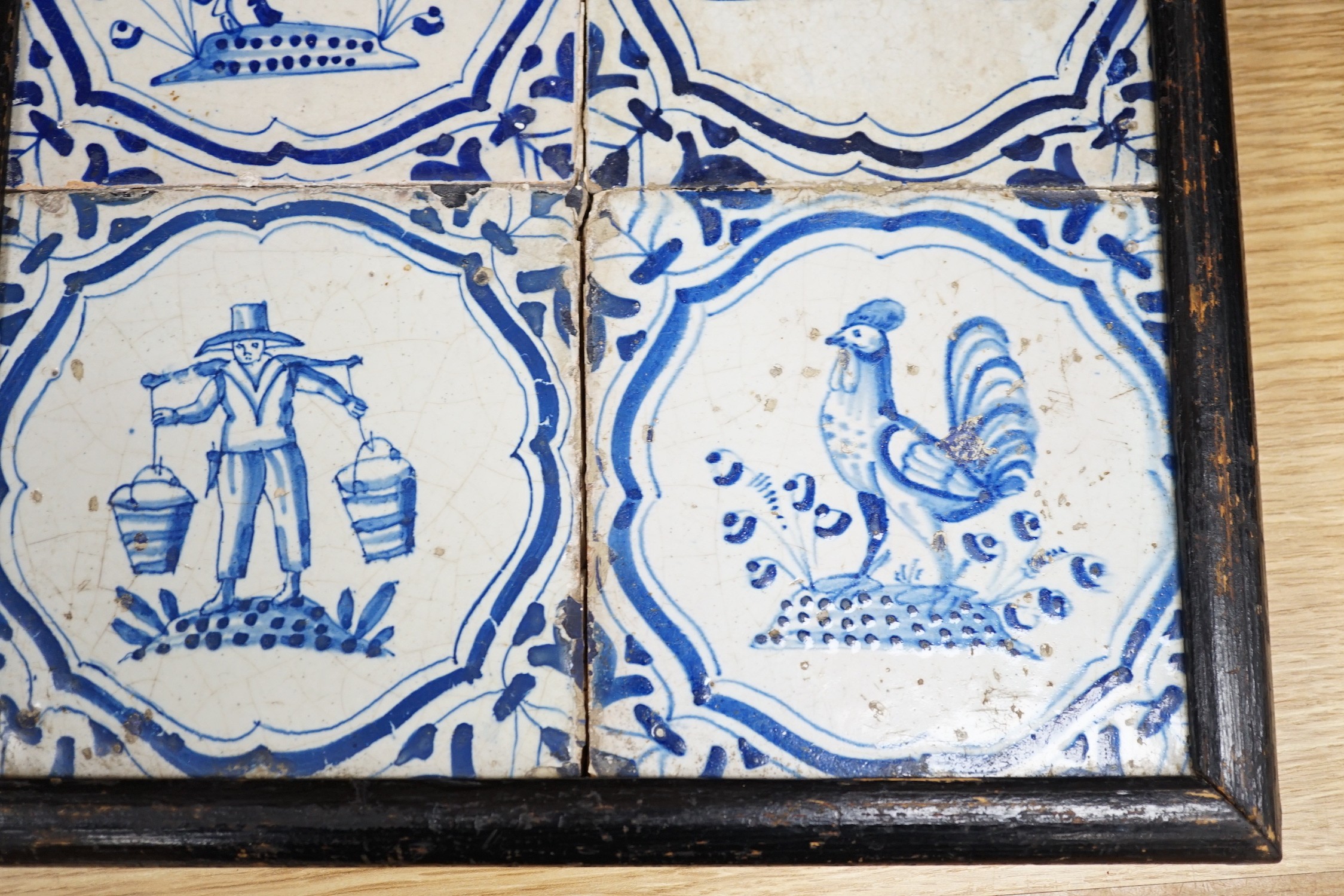 Four 17th century Dutch Delft blue and white tiles, decorated with deer, cockerels and figures within shaped panels (frame 29cm)